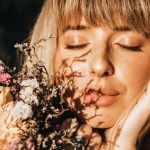 Vibrant healthy woman smelling flowers
