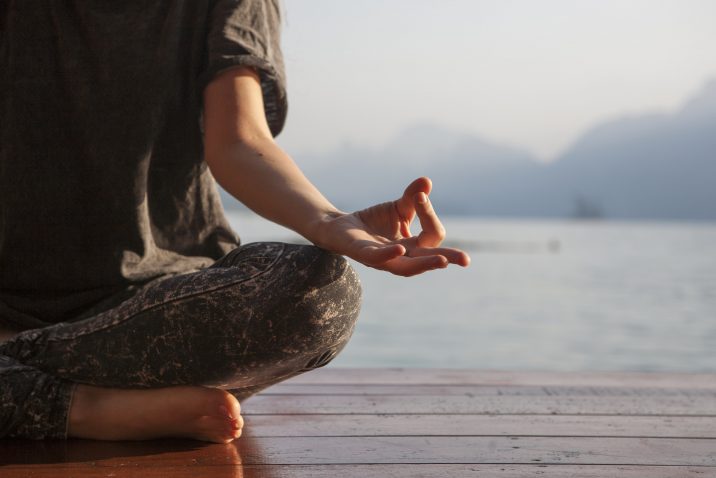 Image of a man meditating in front of a lake