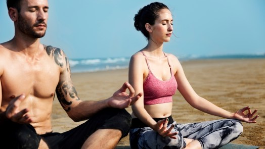 Man and Woman Meditating on a Beach