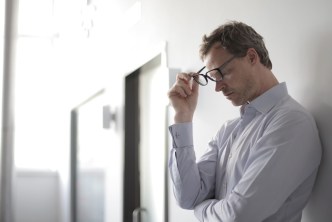 Stressed man taking off glasses