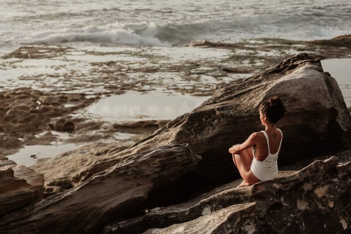 Woman sitting on rocks looking at the ocean