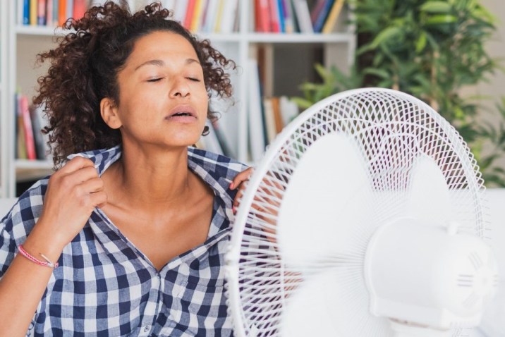 Woman having a hot flash in front of a fan